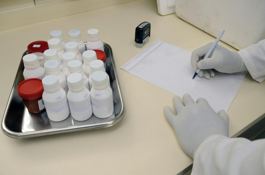 Laboratory technician writing report with samples in a medical lab.